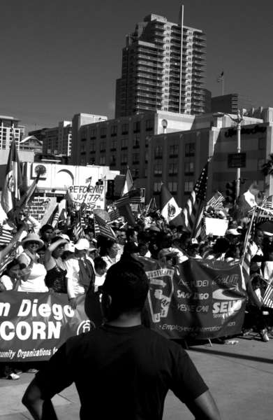 A man observes demonstrators  chants during a downtown San Diego rally.   