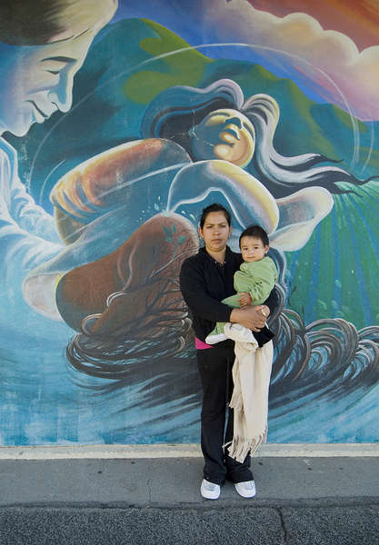 Fabiola Rangel, a migrant worker, stands behind a mural of Cesar Chavez in Sherwood Elementary School.