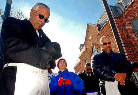 Bobby Bell, 59 (left) and Herald Wilson, 45 (right), members of the Masonic Lodge, bow their heads during a prayer outside the Motsville town square. Bell lead a march with other members of his lodge  for a special Martin Luther King Jr. celebration service.