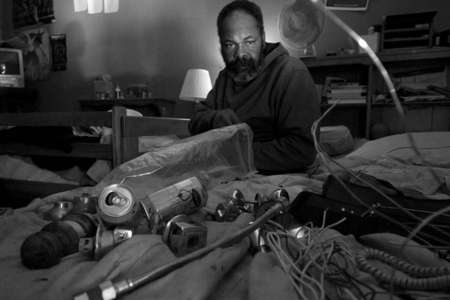 Mahir, takes a moment to reflect as he works on dissembling door nobs for brass and metals. They place the waste items they find and deconstruct from dumpsters and warehouses on their bed to work on. Mostly, because they do not have the space to place these items somewhere else when working. 