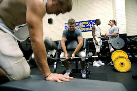 Mitchell Henry, center, takes on 120 pounds during football training. Mitchell, like his teammates at Elizabethtown High School, is expected to incorporate a high-speed and heavy-weightlifting workout in his routines. The football team's goal: keep its strength throughout the season, something Mitchell takes very seriously because of his college football aspirations. 